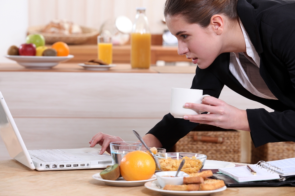 business-woman-on-laptop-eating-breakfast